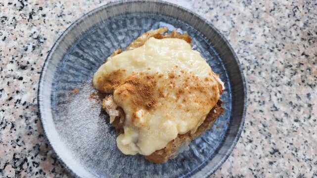 Tasty apple strudel sits on ceramic plate with sweet vanilla sauce. Fresh apple strudel sprinkled with ground cinnamon and powdered sugar serves for delicious sweet breakfast in local cafe.
