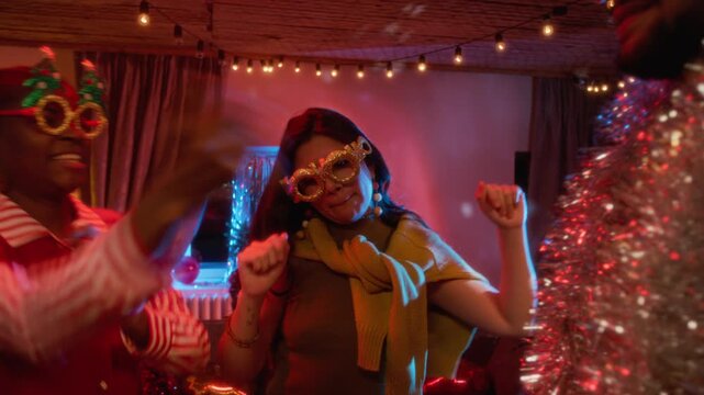 Diverse young adults dancing and blowing noisemakers at festive Christmas party. Clip suited for holiday marketing, event promos, and seasonal winter advertising campaigns