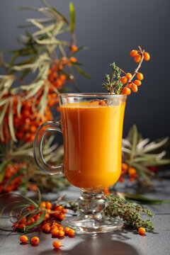 Glass mug of sea buckthorn juice with fresh berries.
