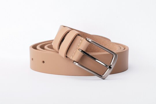 Beige smooth leather belt coiled with a classic rectangular metal buckle on a white background