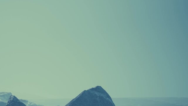 Mountains in a natural setting during the day. The sky has a light blue color, and the peaks are defined against the horizon. The landscape reflects nature and open space.