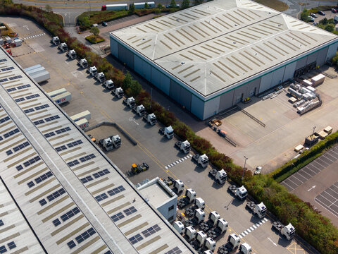 Stafford, United Kingdom - 23 August 2026: Aerial view of Redhill Business Park showing rows of parked semi-trucks and large industrial warehouse buildings.