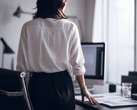 Female graphic designer standing up from her desk in a modern creative office at sunset