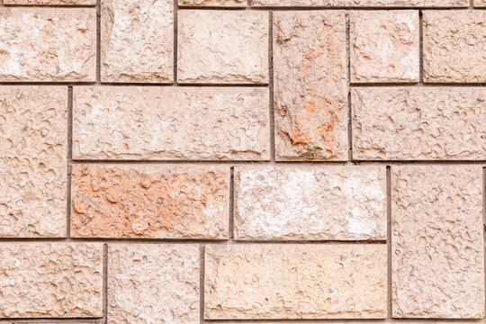 Rough cut stone blocks forming a textured wall surface, displaying natural variations in color and shape, suitable as a background or architectural element