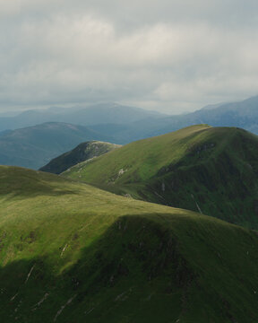 View of the rolling green mountain ridges of the Nantlle Ridge under a cloudy sky in Nantlle, Wales, United Kingdom.
