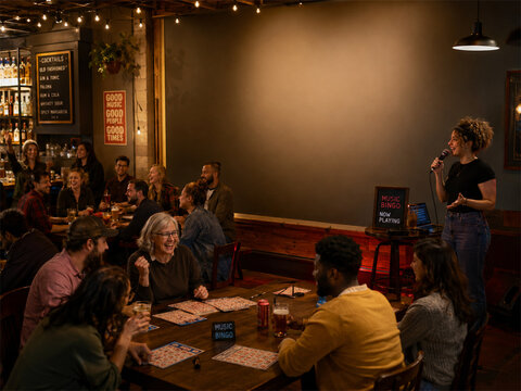 Music bingo night at a cozy bar with groups of friends gathered around tables as a host leads the game and warm string lights create a lively social evening full of laughter and connection