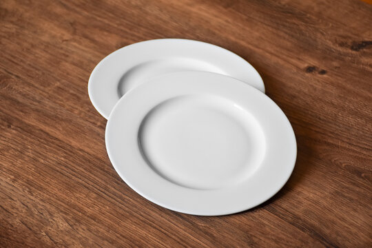 Ceramic white flat plate for food on wooden table top view
