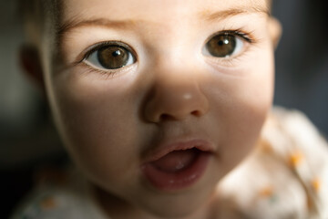 Tiny baby stares wide eyed with wonder at camera capturing pure innocent moment in soft warm light