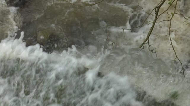 Turbid river rapids churning white foam over submerged rocks in nature close
