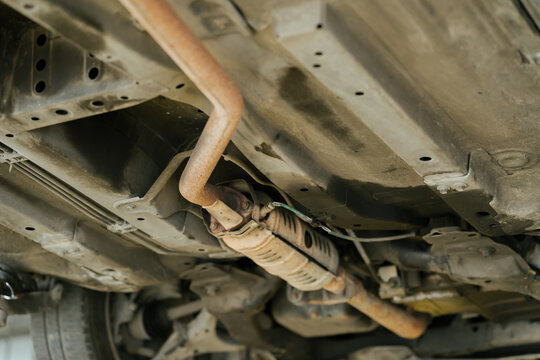 Rusty catalytic converter component under vehicle chassis view showing feeling of mechanical concern during inspection