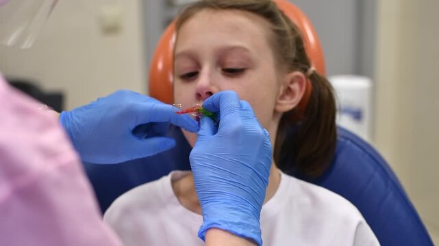 Orthodontist fits removable expansion plate in child's mouth during dental visit and checks appliance placement and comfort.