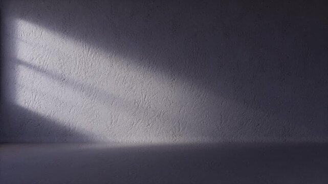 Light moves across a blank wall in a concrete room as the sun rises through the window creating soft shadows, copy space, background