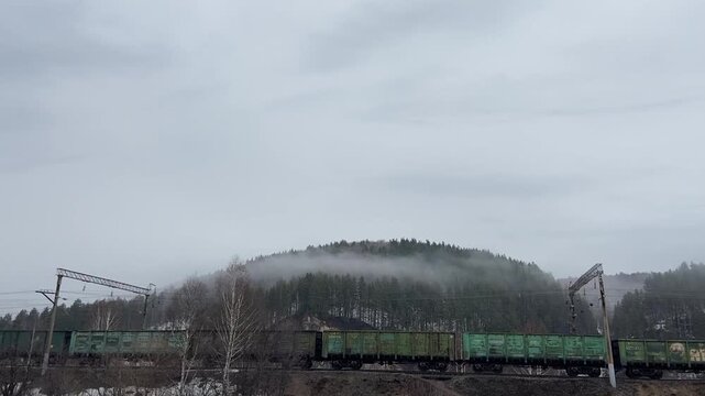 Passenger train passing through snow covered Aygir mountains in winter.