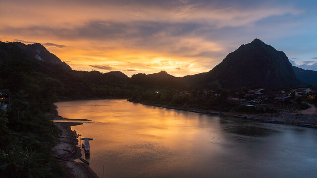 Aerial view of the Nam Ou River flowing through the mountains of Nong Khiaw at sunset, with golden light reflecting on the water in Nong Khiaw, Luang Prabang Province, Laos.