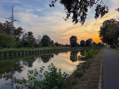 Sunset Reflection on a Tranquil Canal with Bicycle Path and Power Lines, Rijkevorsel, Belgium