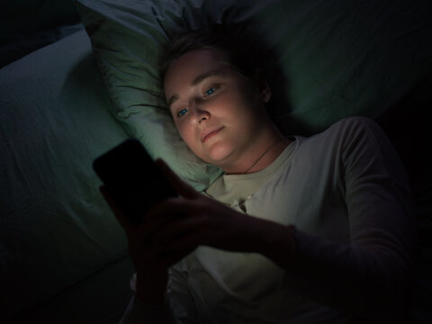 Woman browsing social media on smartphone in bed