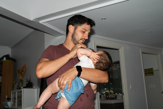 A father holds his baby while feeding him a bottle at home