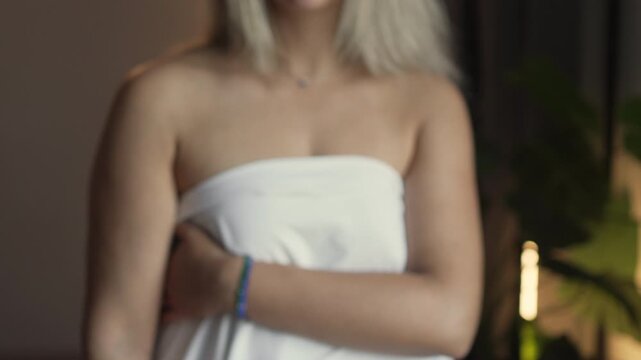 An unidentified adult woman wrapped in a sheet holds out her hand with a sealed condom to protect herself from AIDS and prevent accidental pregnancy.