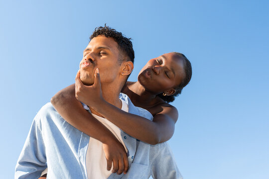 Couple Shares a Playful Moment Outdoors Under Clear Blue Sky