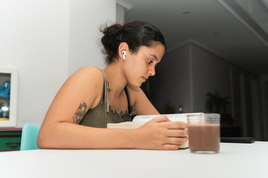 Reading a Book While Enjoying a Drink at Home During the Day