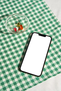 Smartphone Mockup with Vitamins and Supplements on Green Gingham Table