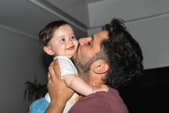 Father hugs and kisses his daughter on the cheek as she smiles