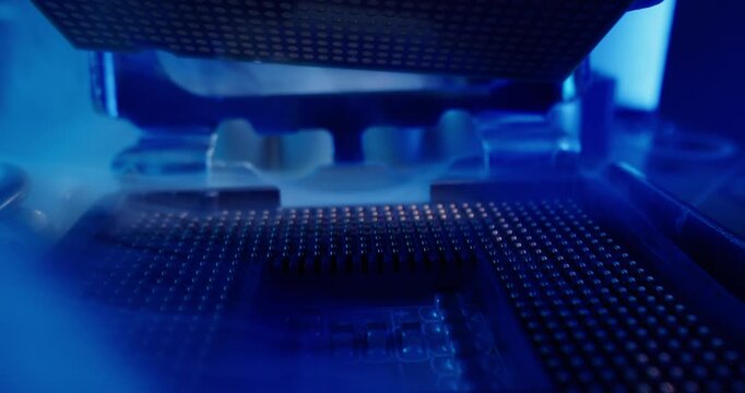 Macro tracking shot of cpu processor being inserted into motherboard socket inside pc case with blue reflective lighting, shallow focus and slow panning motion.