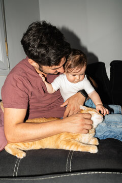 Father and Child Interact With a Cat in a Living Room
