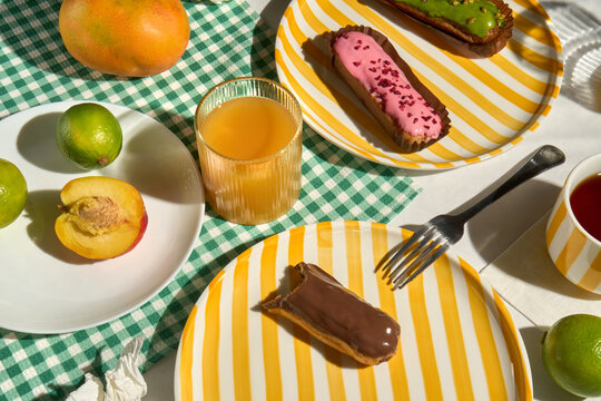 Sunny Breakfast Table with Eclairs, Fresh Fruit and Orange Juice