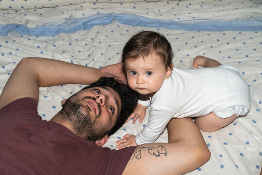 Father and Baby Play Together on Bed