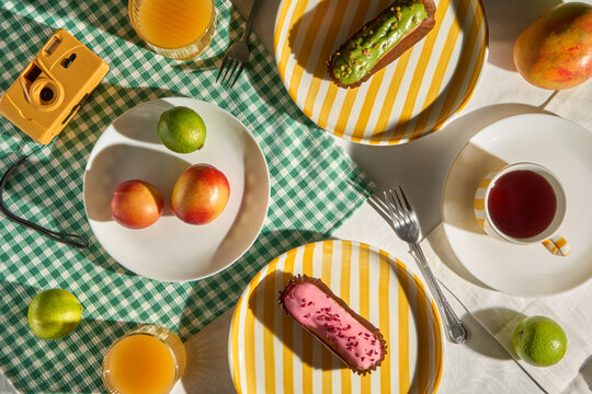 Summer breakfast picnic table with eclairs, colorful fruit and camera