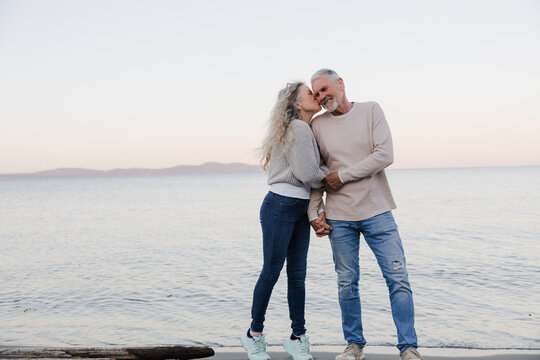Senior couple kissing on the beach at sunset