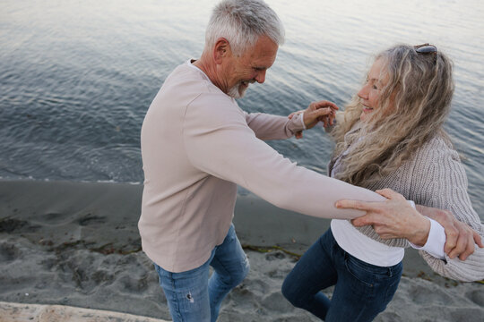Happy senior couple dancing together on a beach at sunset