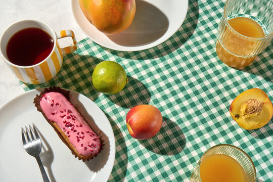 Sunny Breakfast Table with Tea, Orange Juice, Eclair and Fresh Fruit