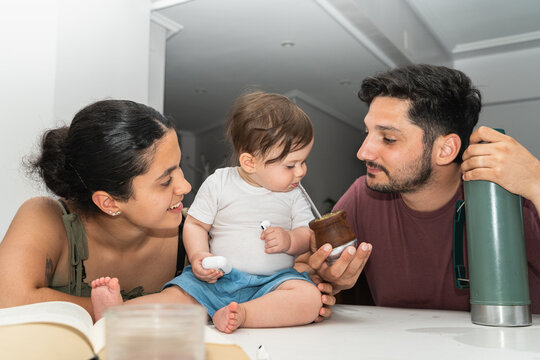 A family with their baby at home. Letting the baby try some mate