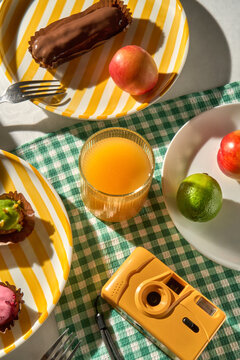 Summer breakfast picnic table with colorful fruit, juice and a camera