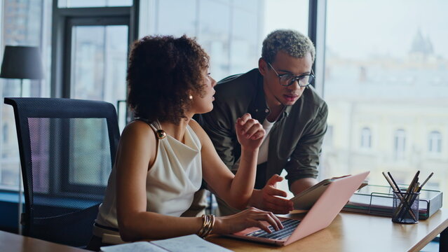 Man and woman analyzing project on laptop. Multiethnic coworkers in office