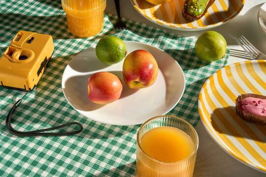 Summer breakfast picnic table with colorful fruit, juice and camera