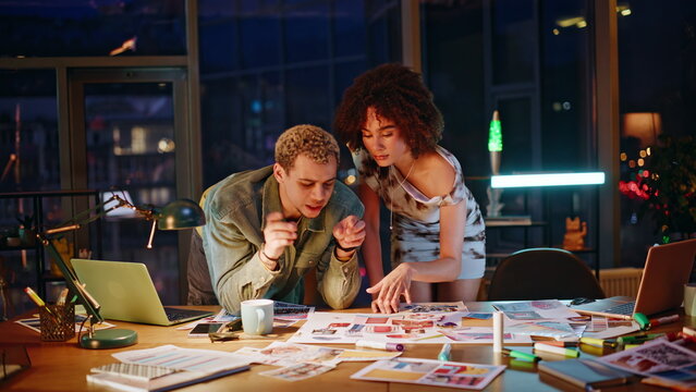 Designers reviewing mood board late night studio. Creatives brainstorming ideas