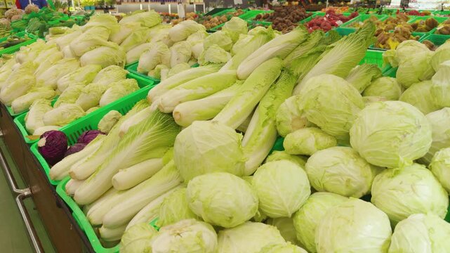 Fresh napa cabbage and green cabbage in large quantities filling crates at a vibrant grocery store produce section, highlighting healthy eating and supermarket abundance