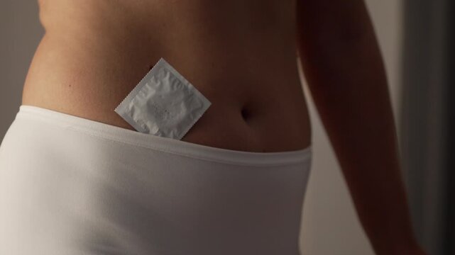 An unidentified adult woman holds a sealed condom to protect herself from AIDS and prevent accidental pregnancy