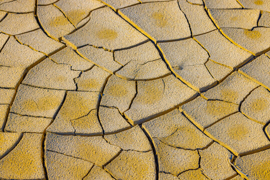 Aerial view of the cracked, arid soil surface near Gora Bokty, showcasing the intricate patterns of parched earth under bright sunlight in Karakiya District, Mangystau Region, Kazakhstan.