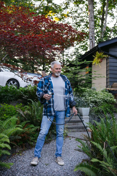 Senior man watering garden with hose in relaxed backyard