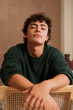 Young Man Sits in a Chair With a Confident Look Indoors