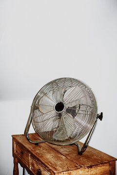 Fan Placed on Wooden Dresser in a Simple Indoor Setting