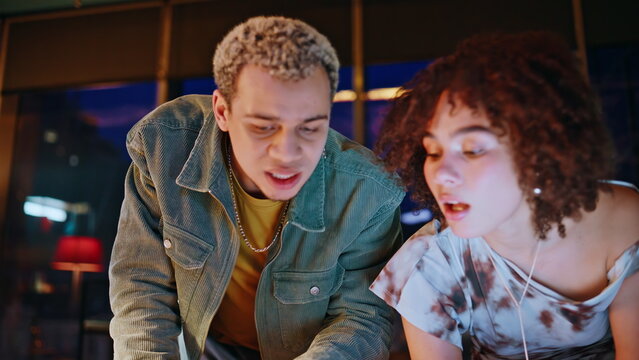 Frustrated coworkers reviewing mood board photos in night office design studio