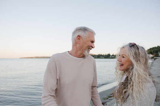 Senior couple laughing together on a calm beach at sunset