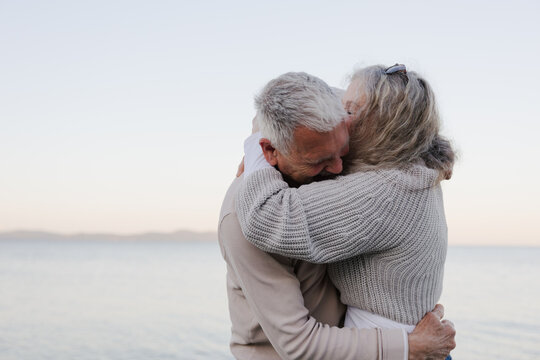 Senior couple hugging on the beach, candid moment of affection