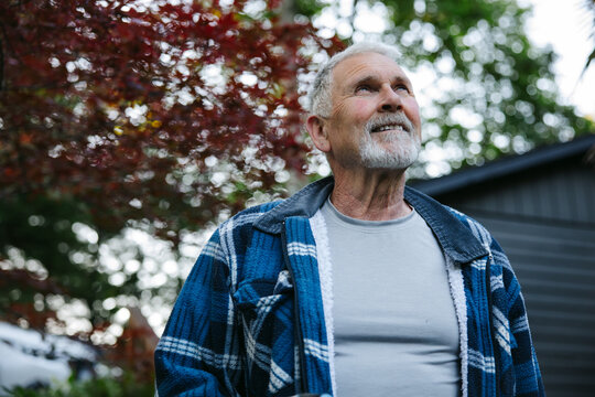 Senior man looking up outdoors with a thoughtful smile