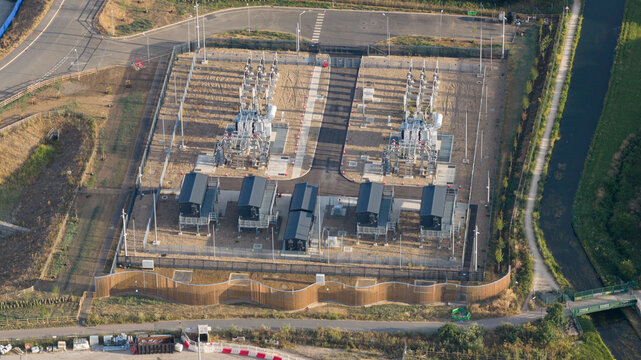 Aerial view of the Google Data Centre in Waltham Cross, featuring electrical infrastructure and modular buildings in a fenced compound near a canal in Cheshunt, England, United Kingdom.